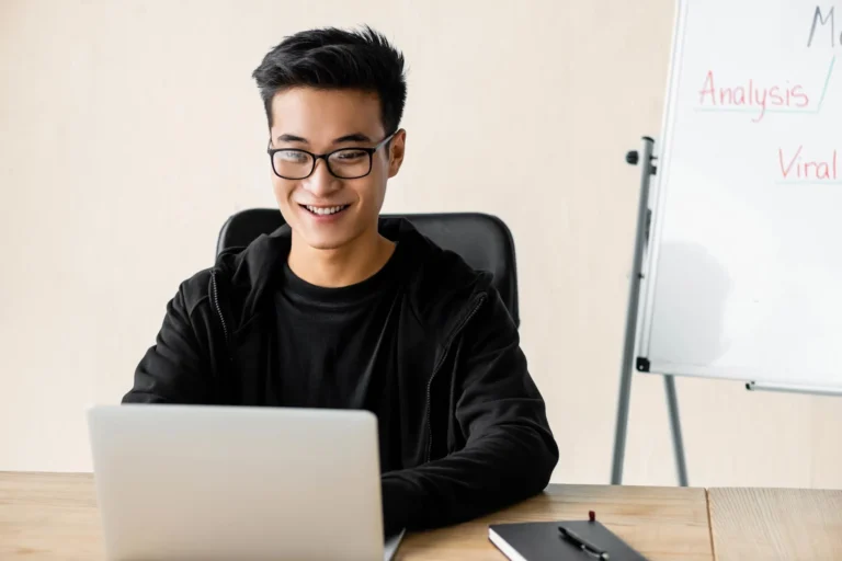 smiling-seo-manager-in-glasses-sitting-at-table
